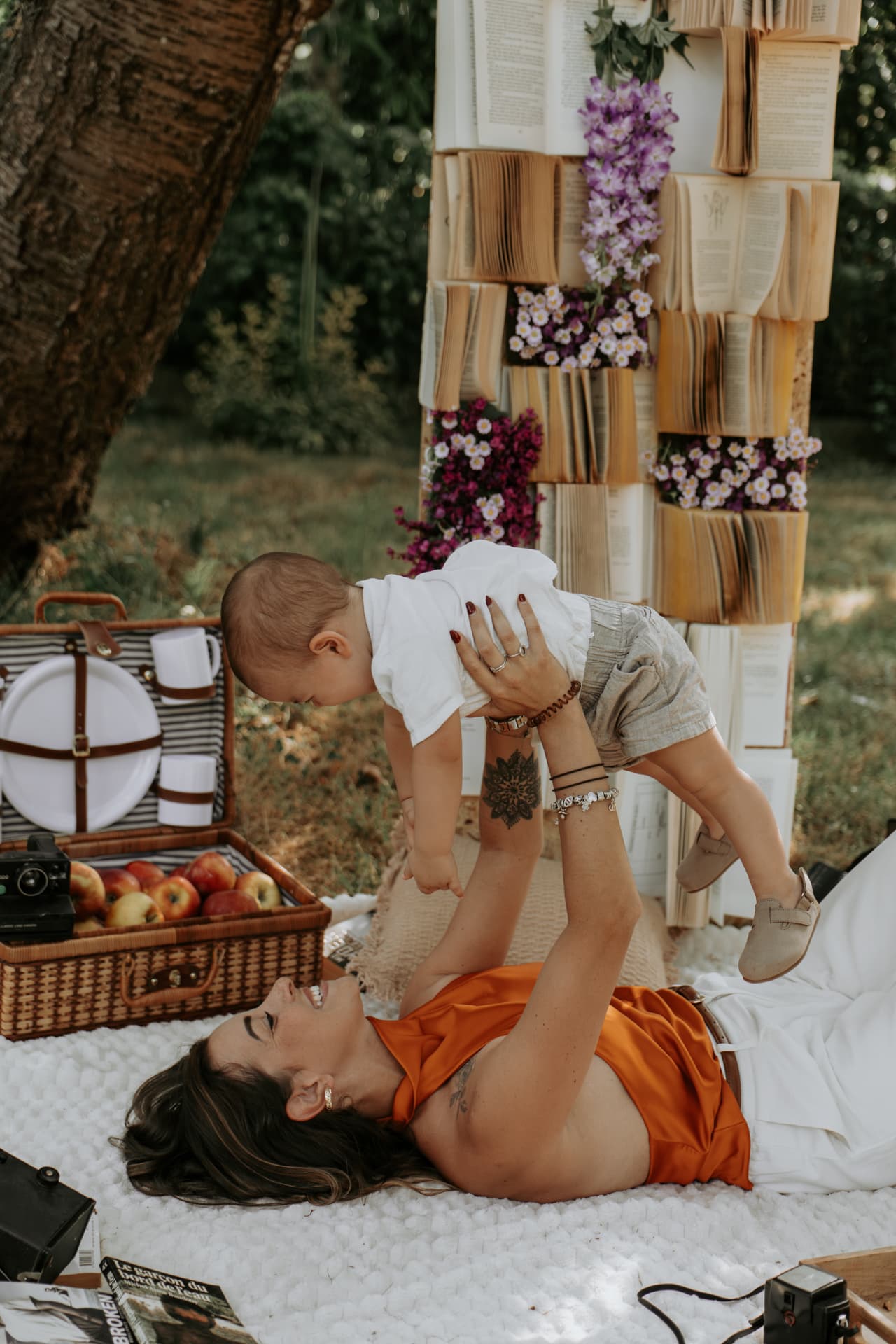 Maman soulevant son bébé sur un plaid lors d'une séance photo en extérieur